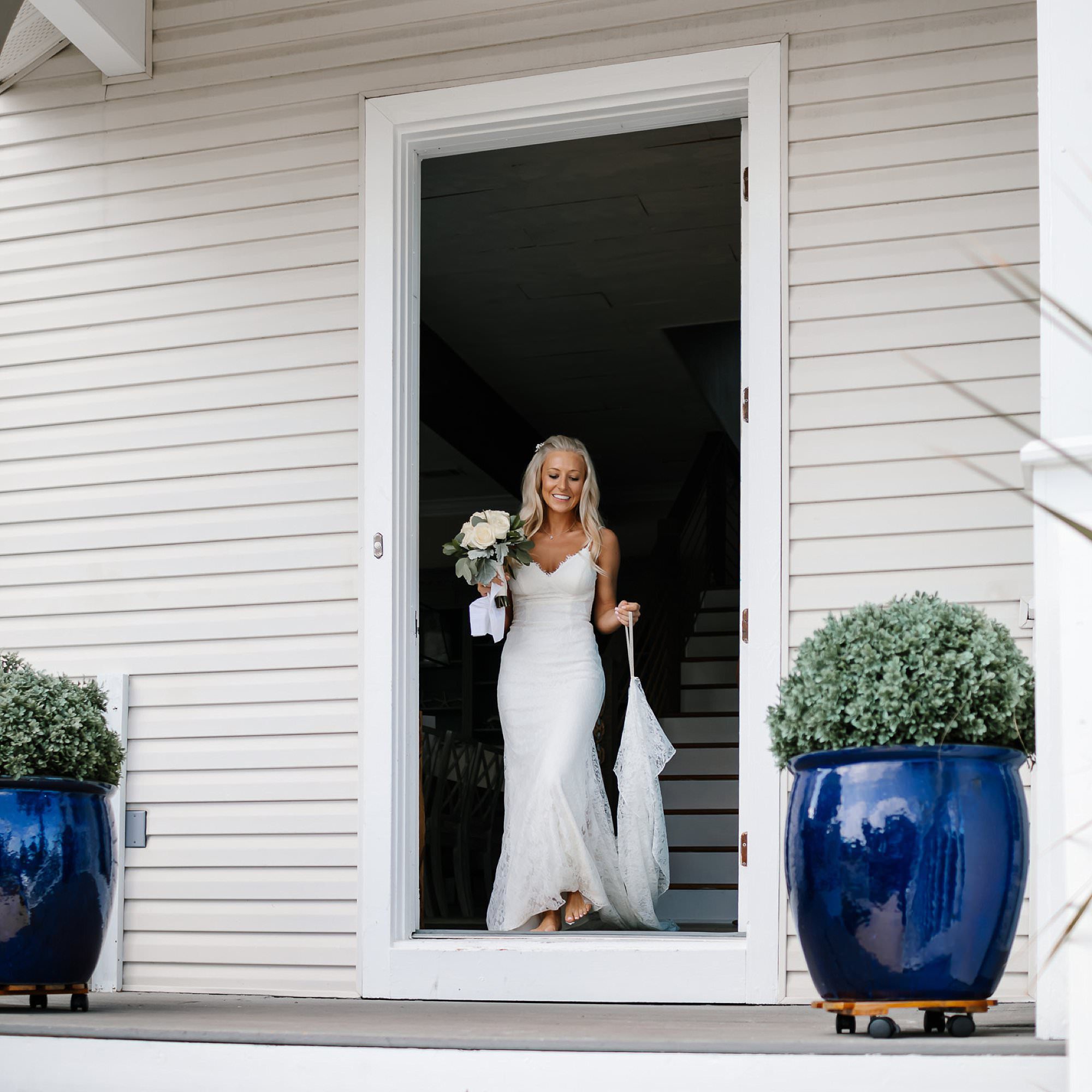 Bride in white lace sheath dress in doorway of White Whale Beach House in Destin Florida