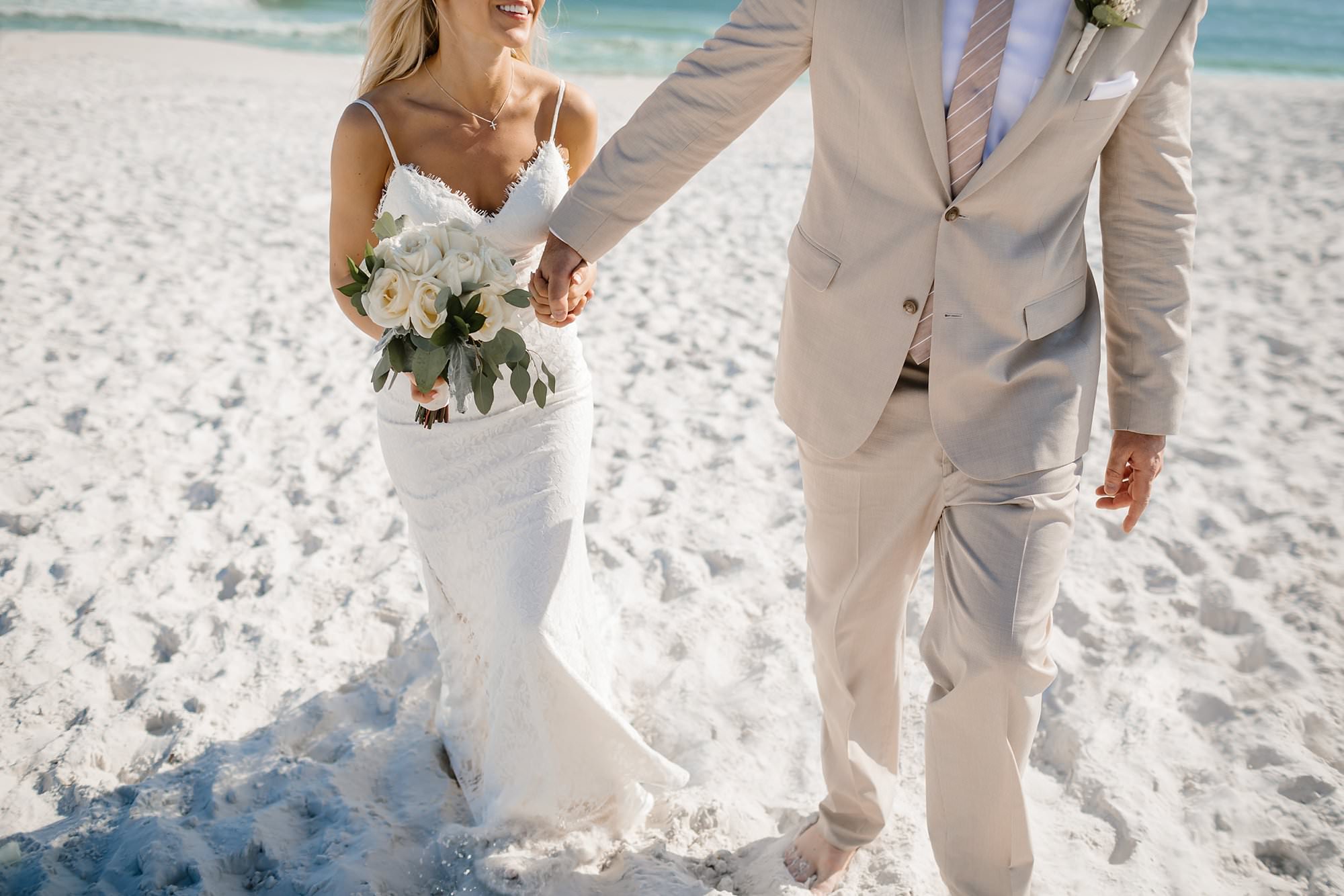 Portraits of bride and groom holding hand walking on the beach in Destin Florida