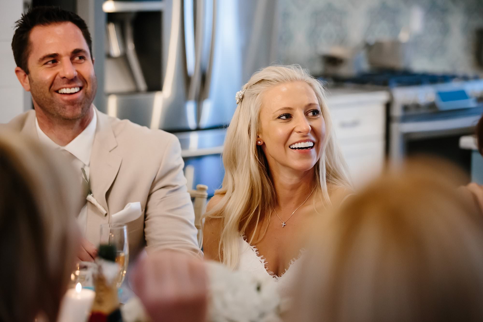 Bride and groom laughing at speeches during reception dinner