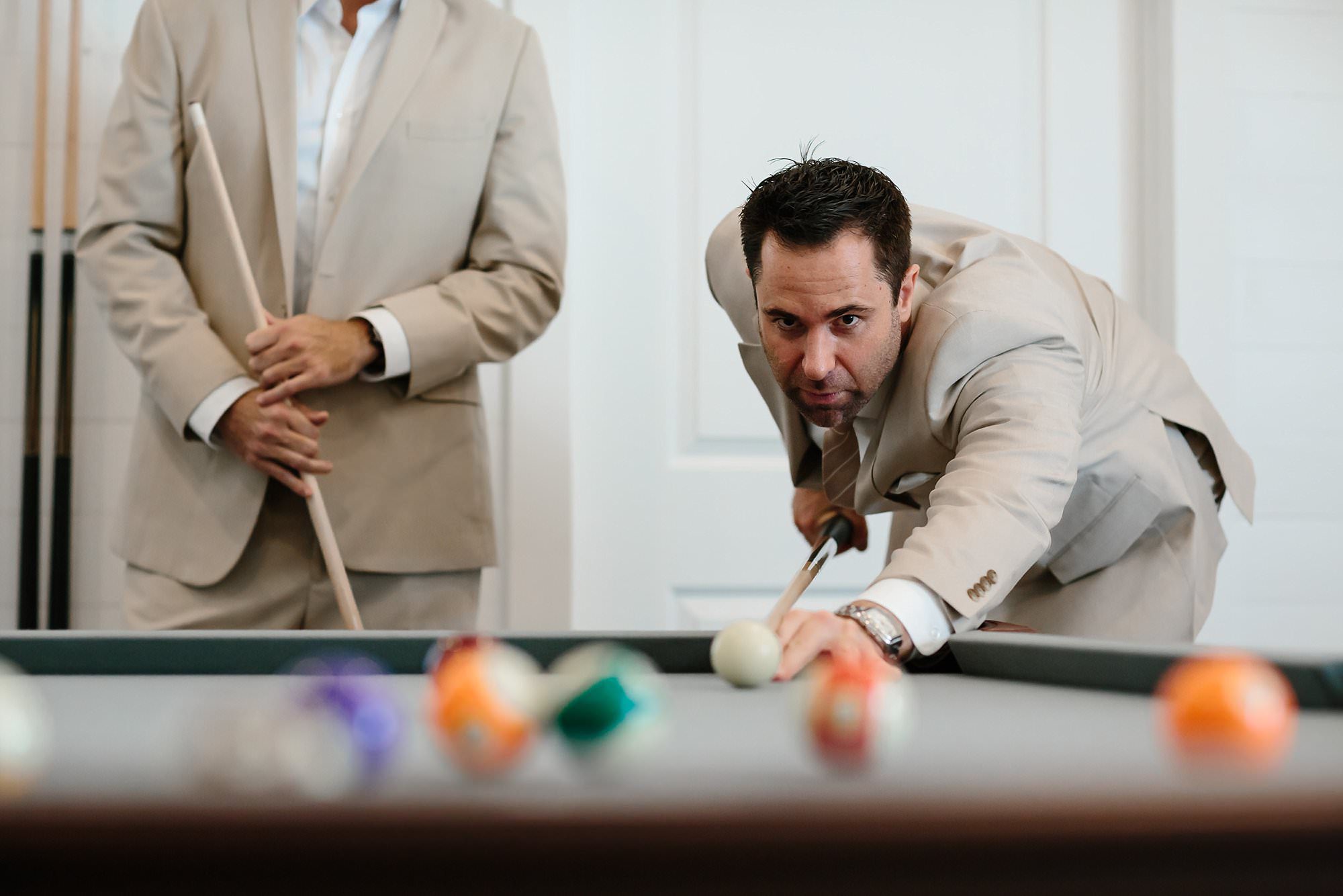 Low view of Groom lining up a shot while playing pool with best man