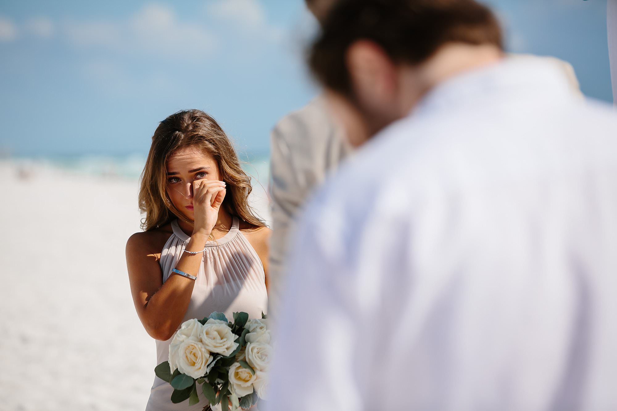 Bridesmaid wiping away tear at beach ceremony in Destin Florida