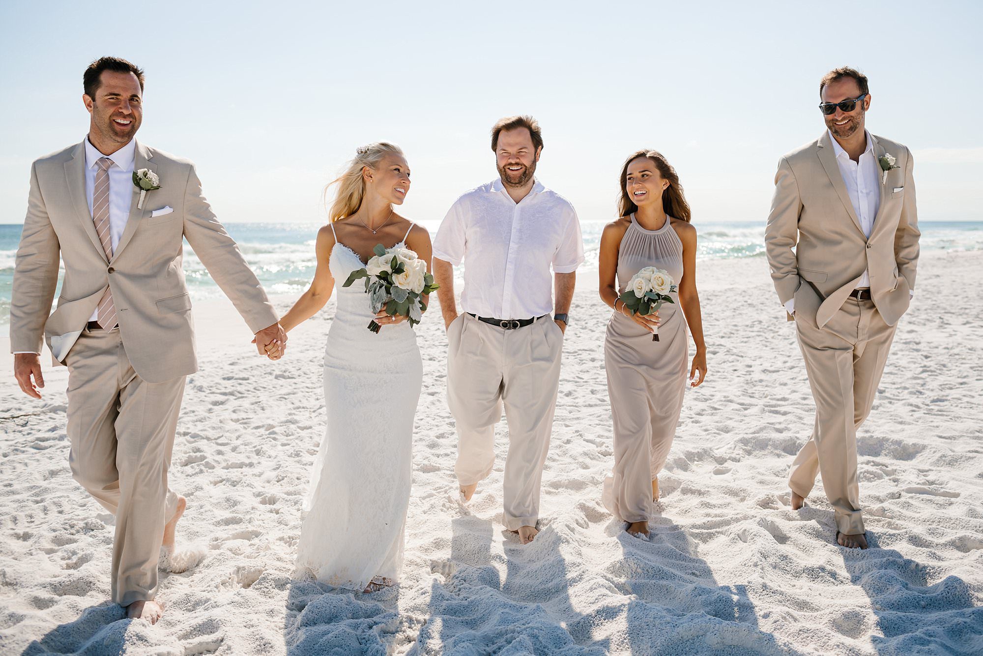 Small wedding party walking on the beach in Henderson Beach State Park after ceremony