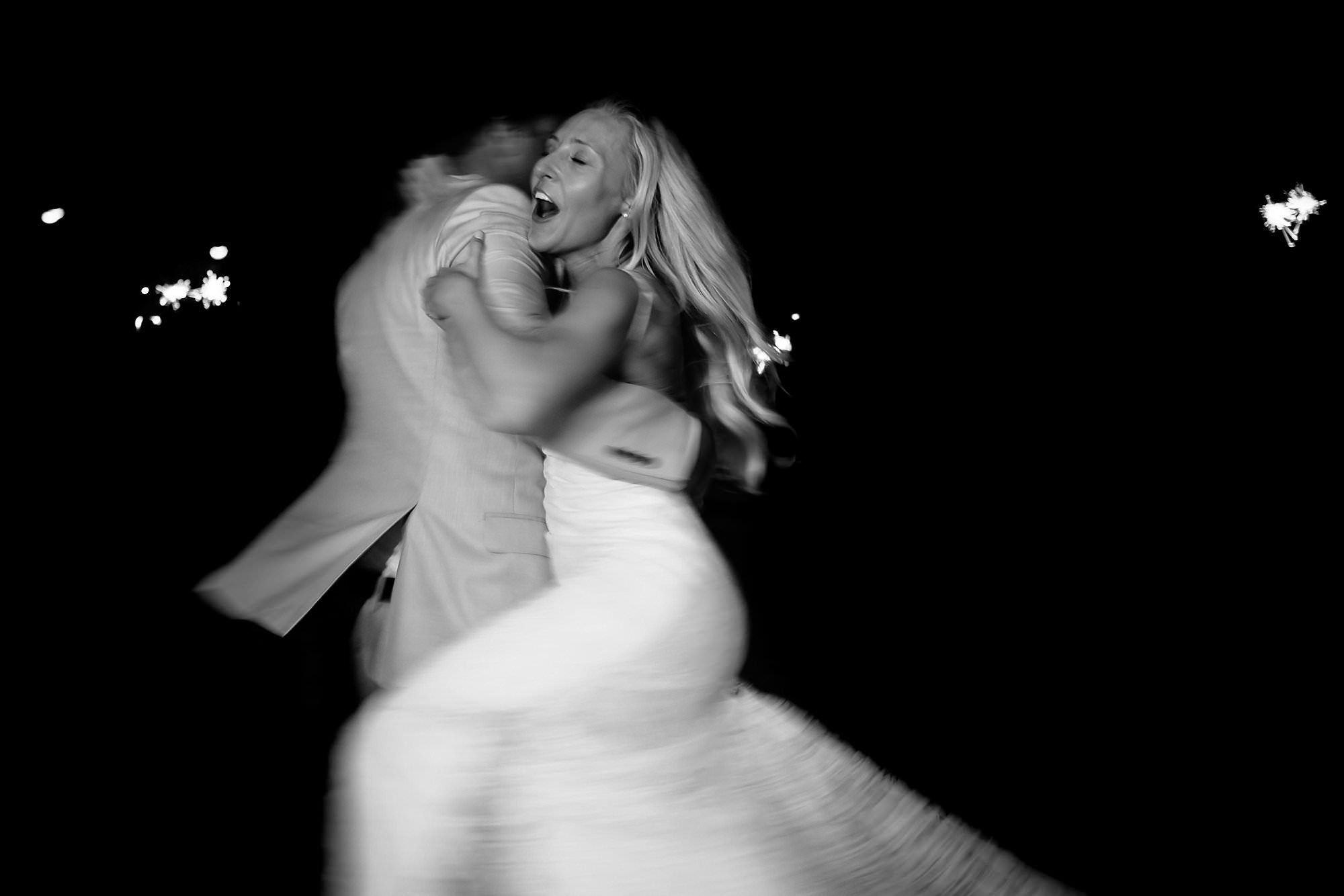 Black and white long exposure portrait of Groom spinning bride during sparkler exit in Destin Florida