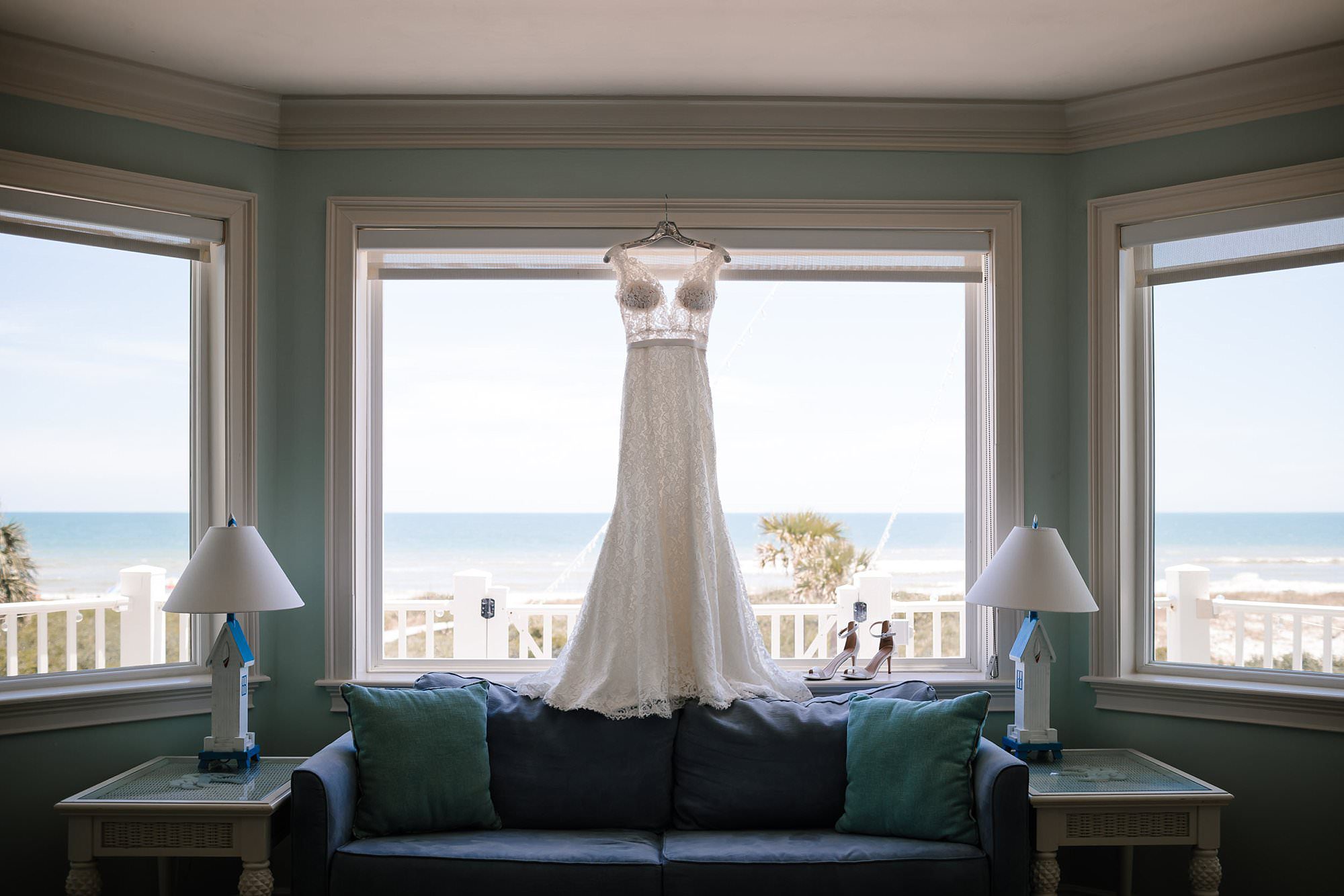 Wedding Dress hanging in window in front of beach