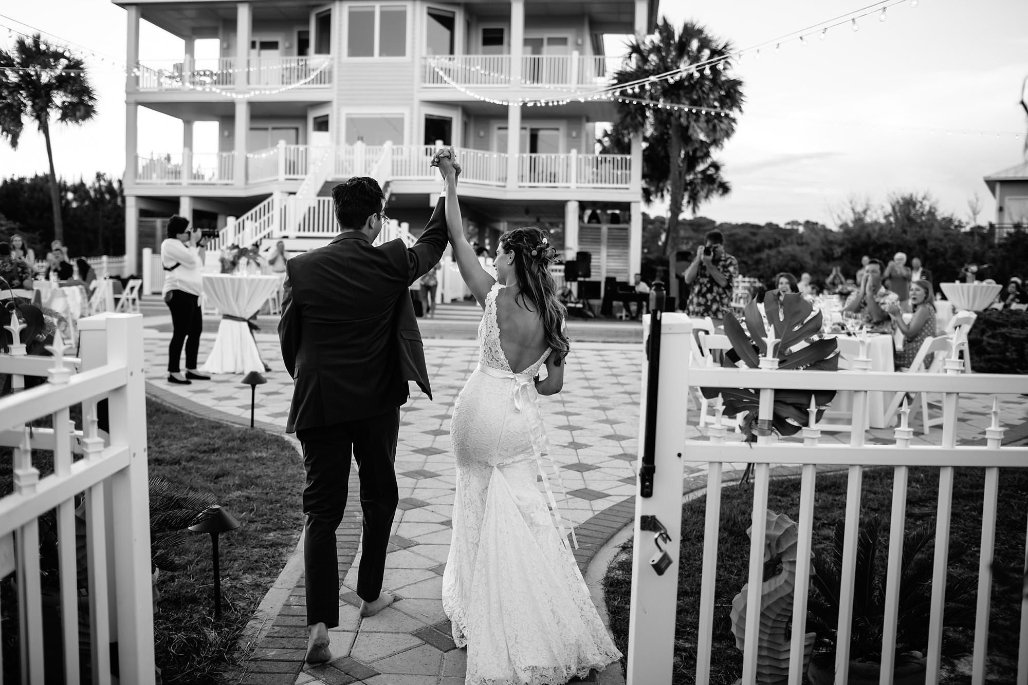 Bride and Groom enter outdoor reception around pool at Aisle of Palms beach house on St. George Island