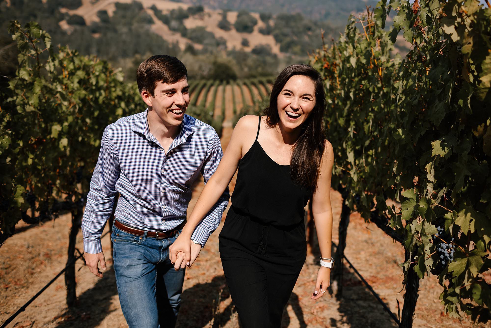 Newly engaged couple walk hand in hand through the Mont La Salle vineyard