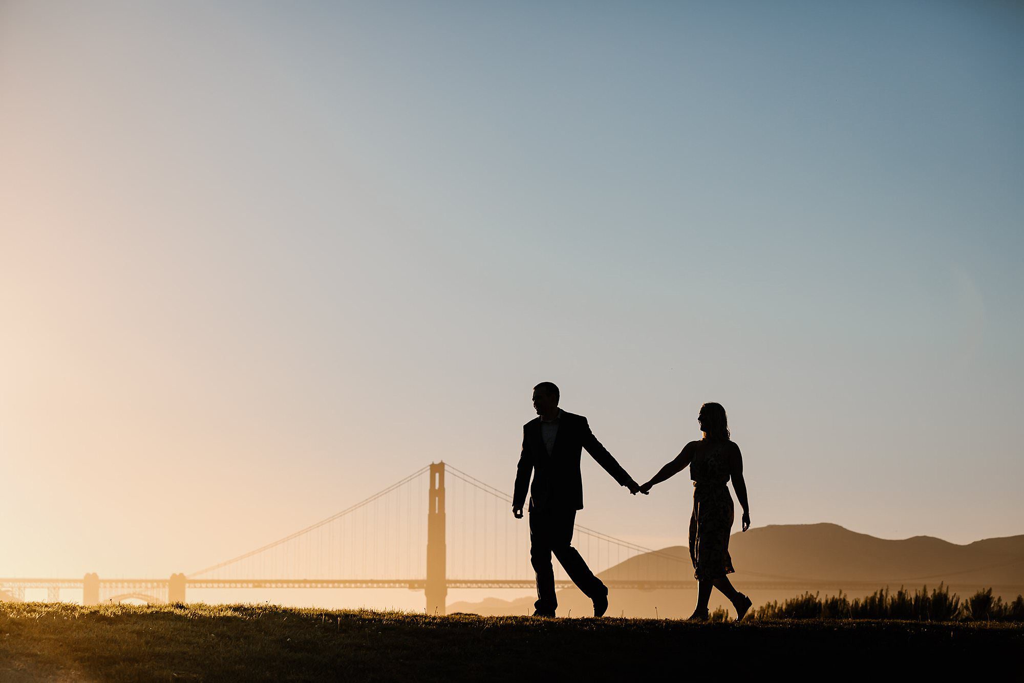 Aubrey leads his fiancé Skylar across a hill overlooking Golden Gate Bridge at sunset
