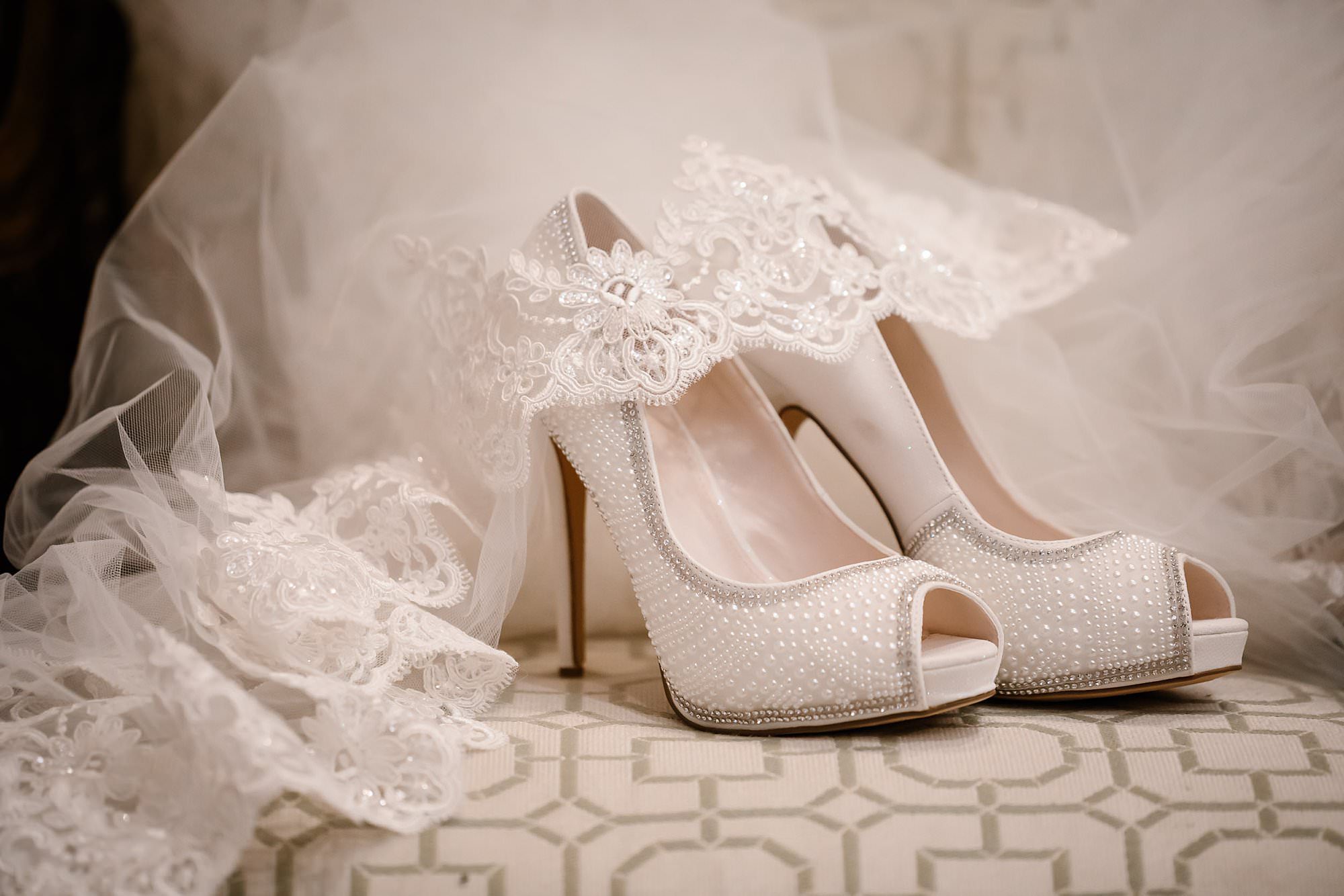 Lace veil and white heels on a chair in the bridal suite