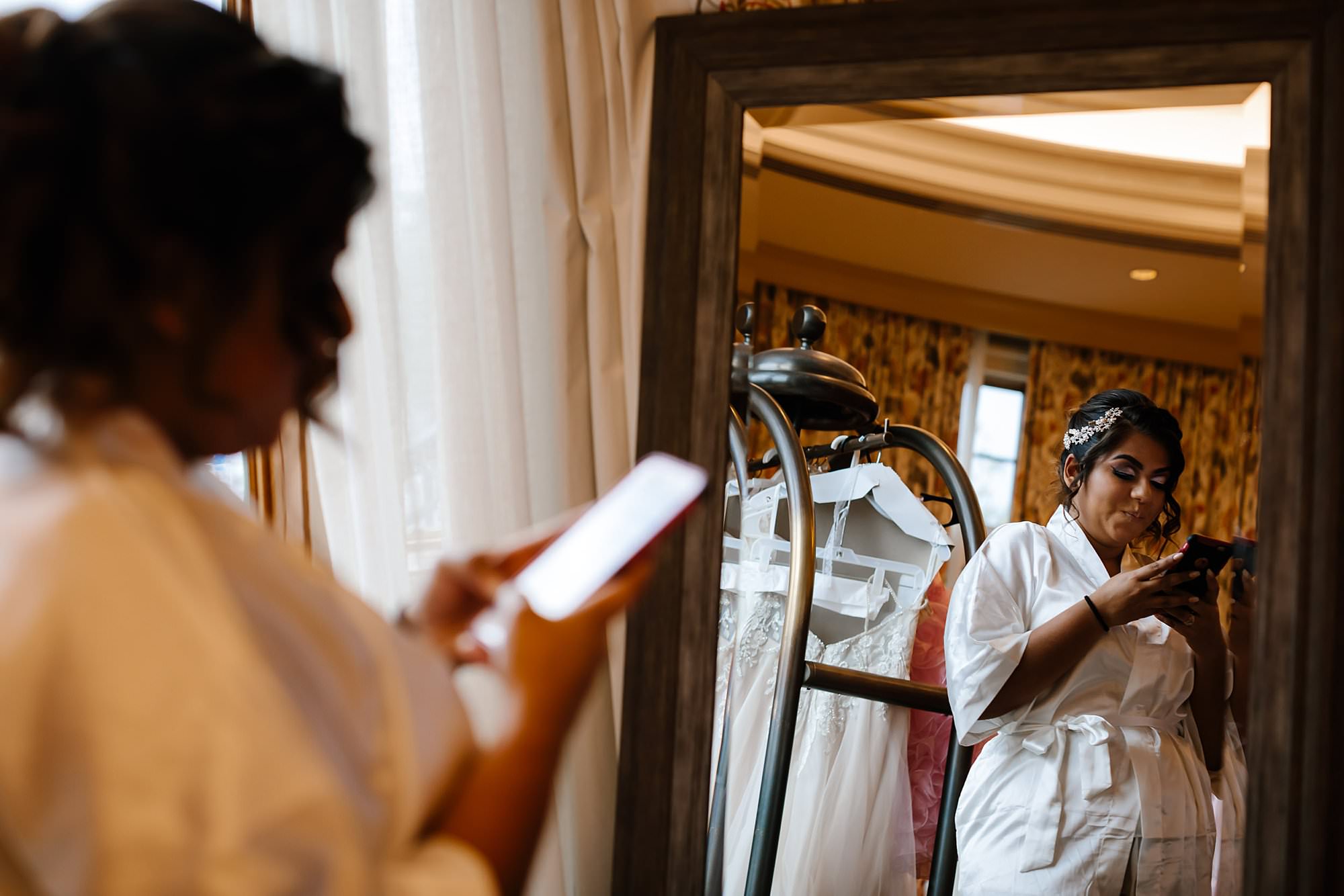 Bride texting while being reflecting in the mirror