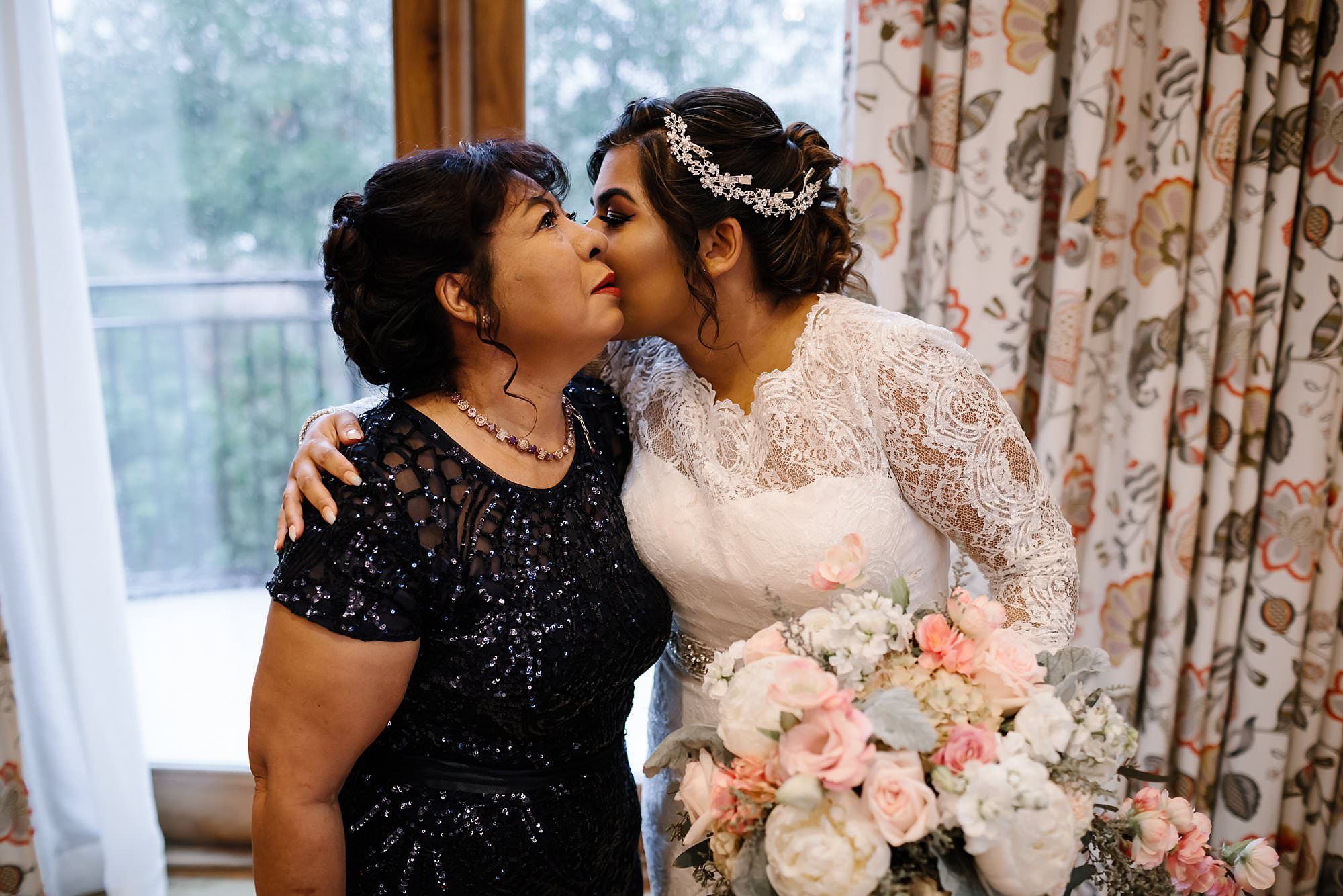 Bride kissing her mom before walking out the door to see the groom