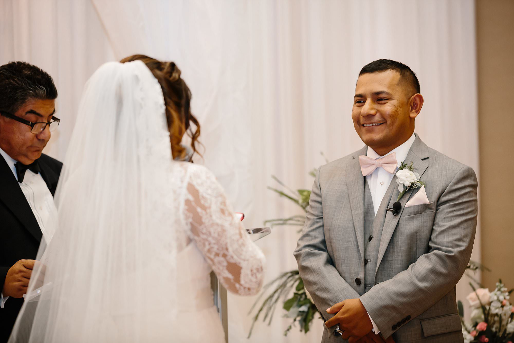 Groom smiling at bride reciting vows