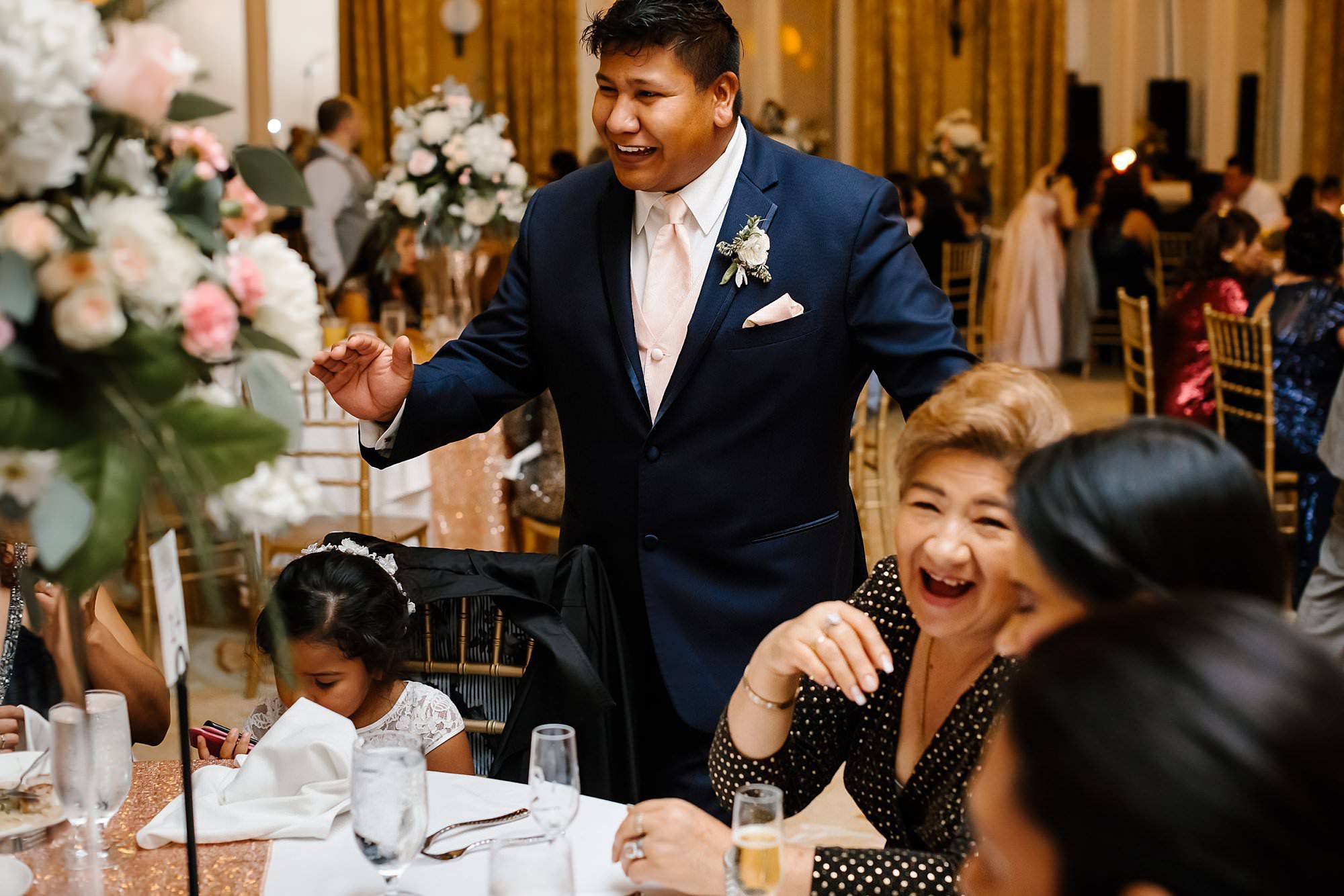 Best man laughing with guests at reception