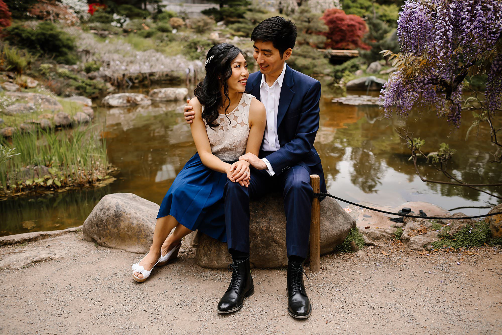 Engaged couple sitting together in front of the pond in Hakone Estate gardens