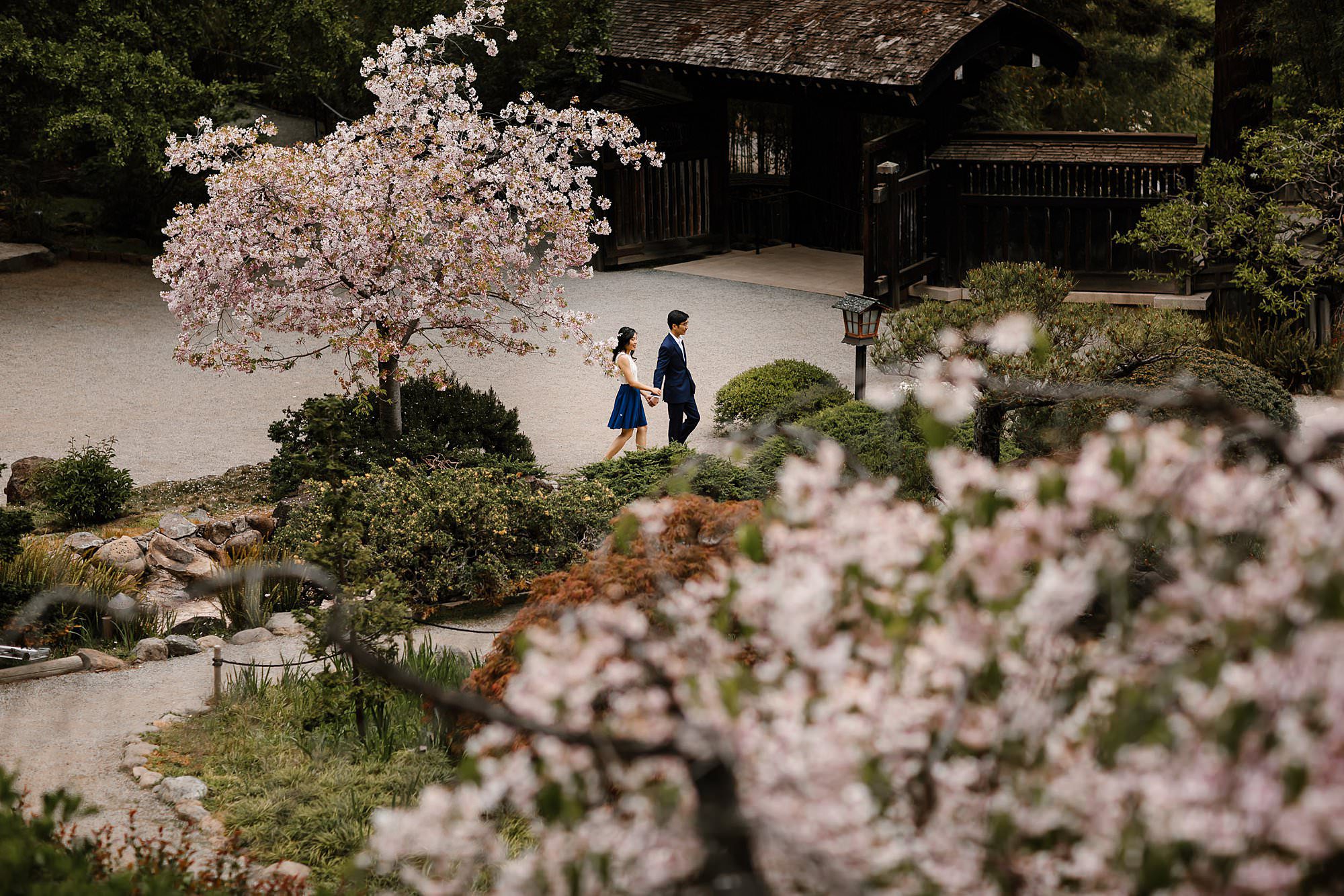 Engaged couple holding hands while walking on the other side of the gardens at Hakone 