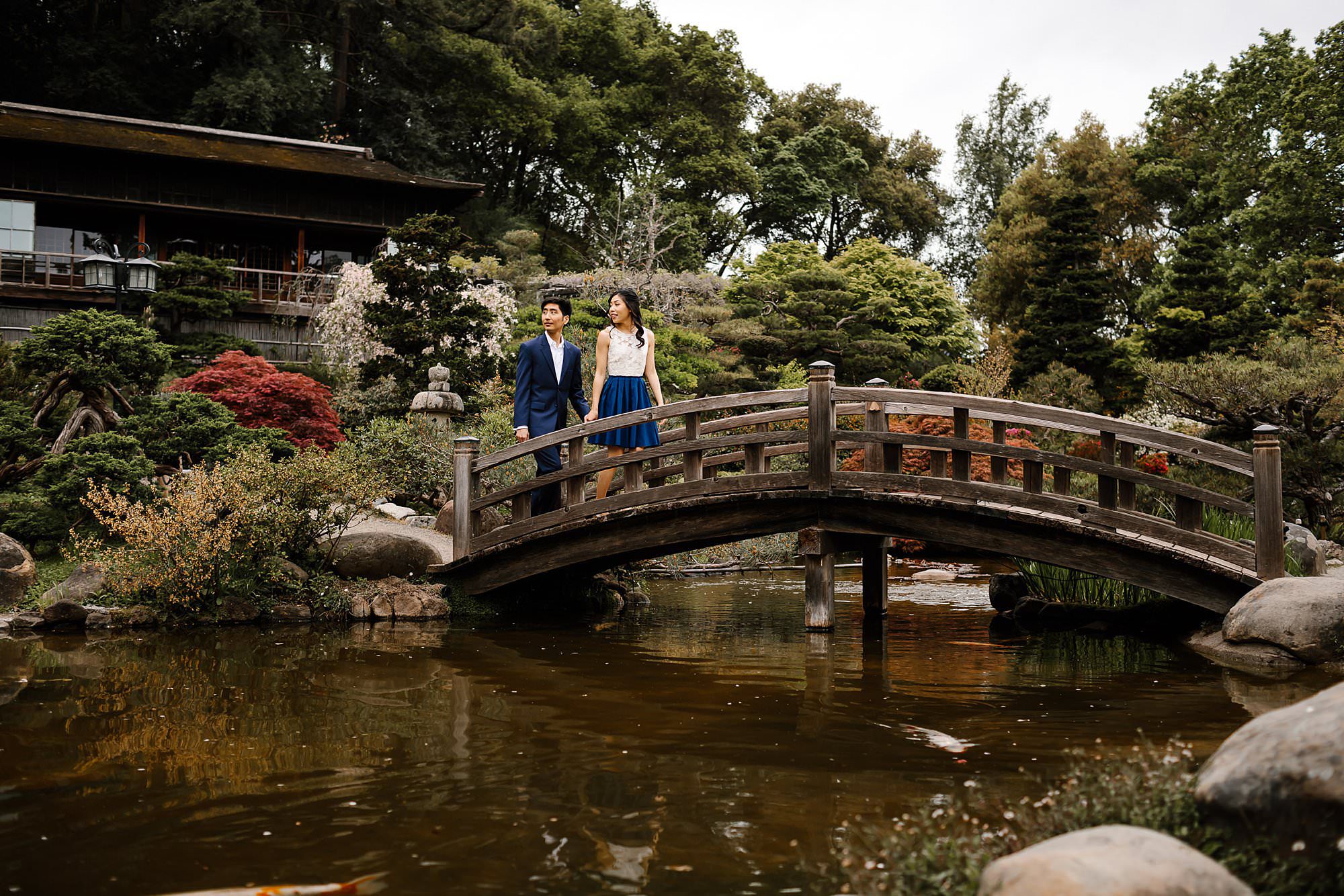 Engaged couple walking over bridge in Hakone Estate gardens