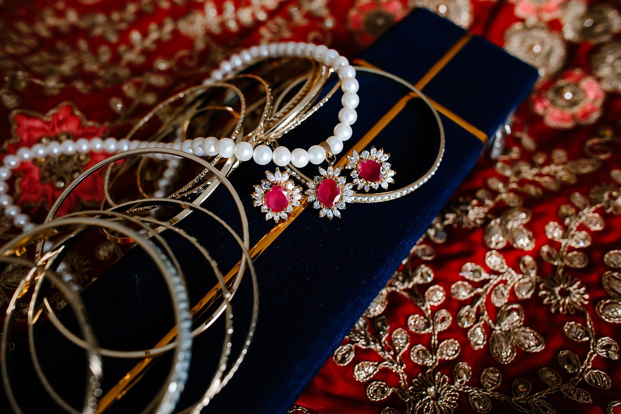 Pearl and ruby necklace with gold bangles lying on hindu saree