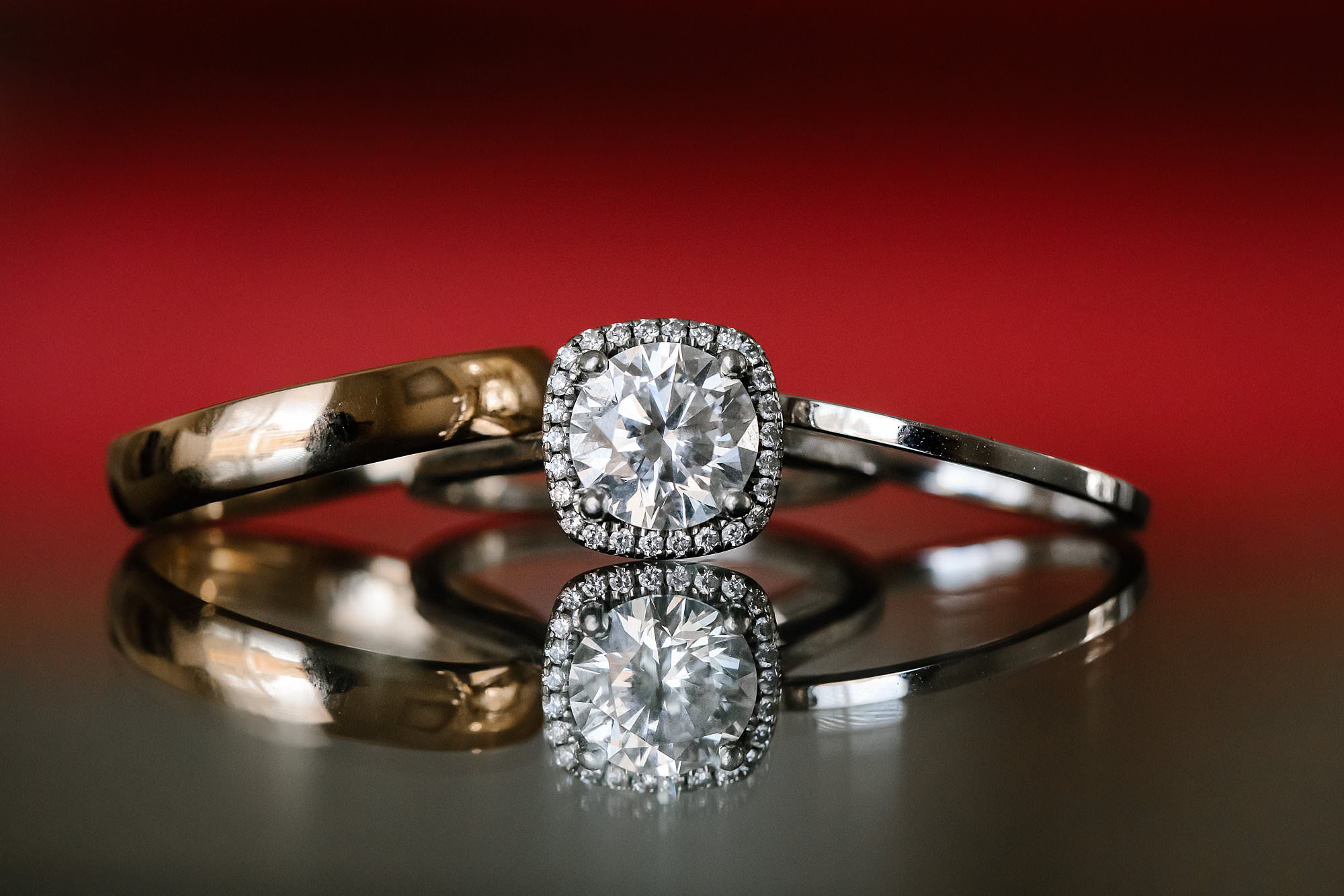 Diamond engagement ring and wedding bands reflected on a table