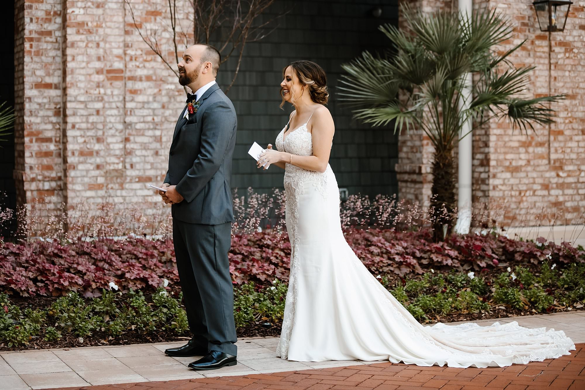 Bride stands behind groom during first look to read him a letter in front of the Henderson Resort in Destin
