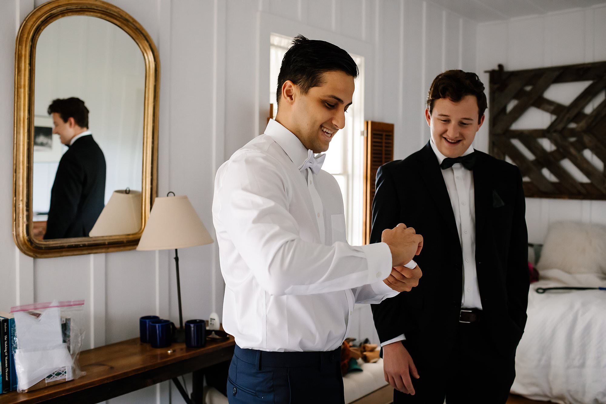 Groom and his groomsman laughs at his attempt to fold a pocket square 