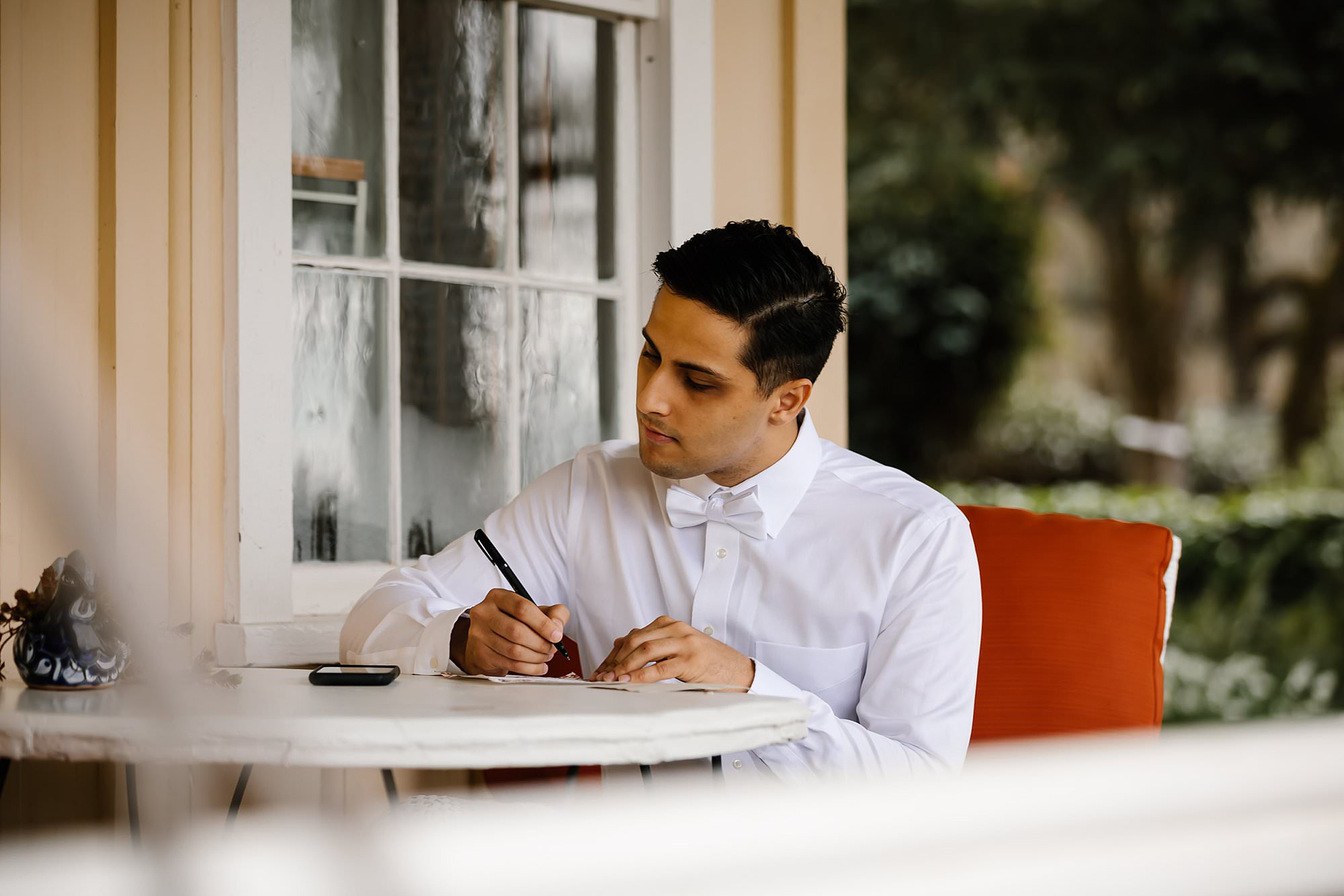 Groom sits on the porch at Beltane Ranch to write a letter to his bride 