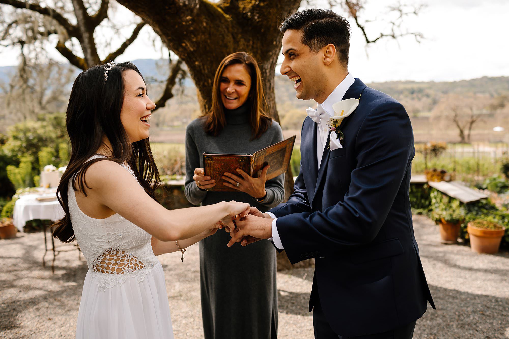 Bride and groom laughing as they exchange rings during their Beltane Ranch elopement