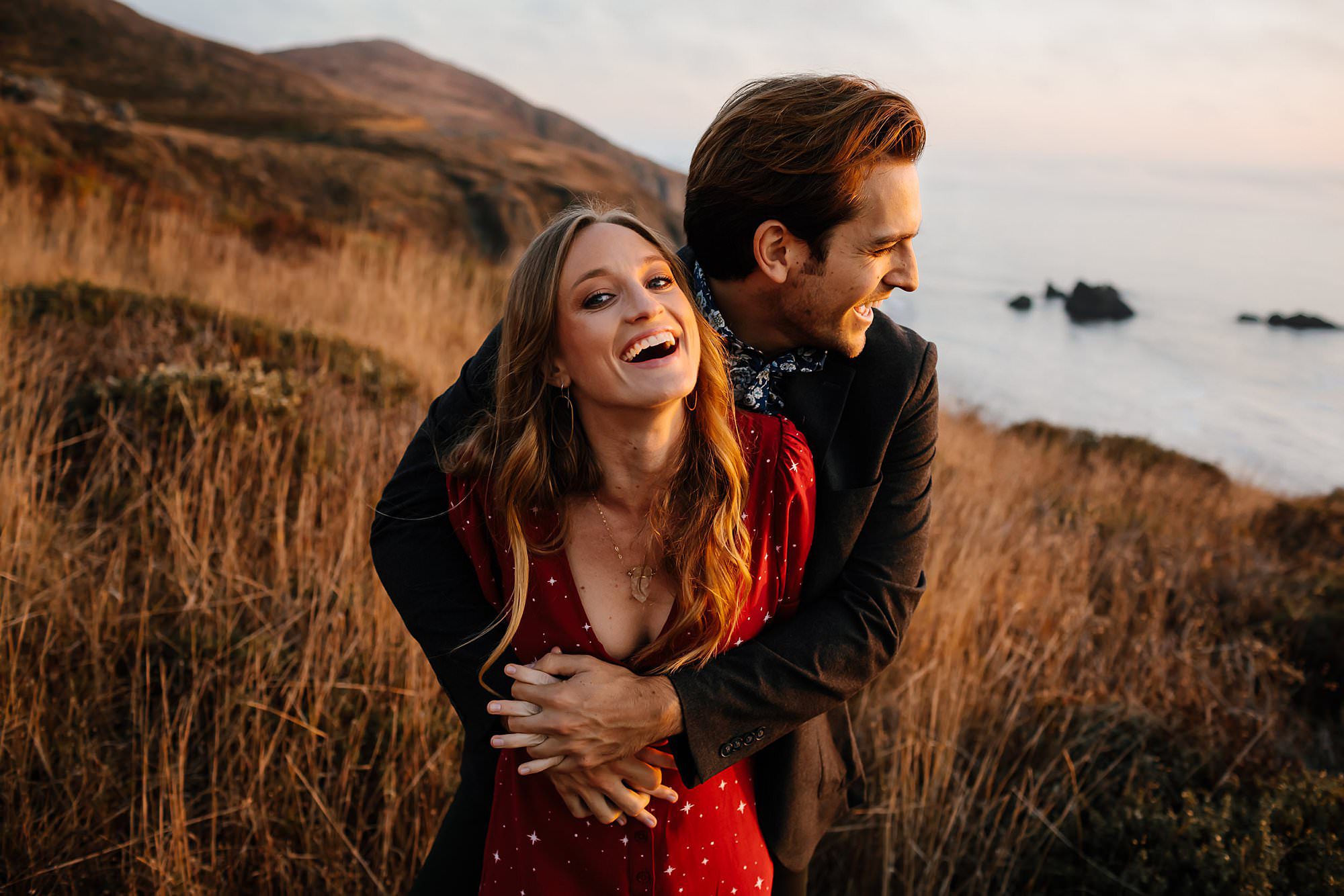 Austin and Casie laughing in the tall grasses on the cliffs above Goat Rock Beach in Jenner CA