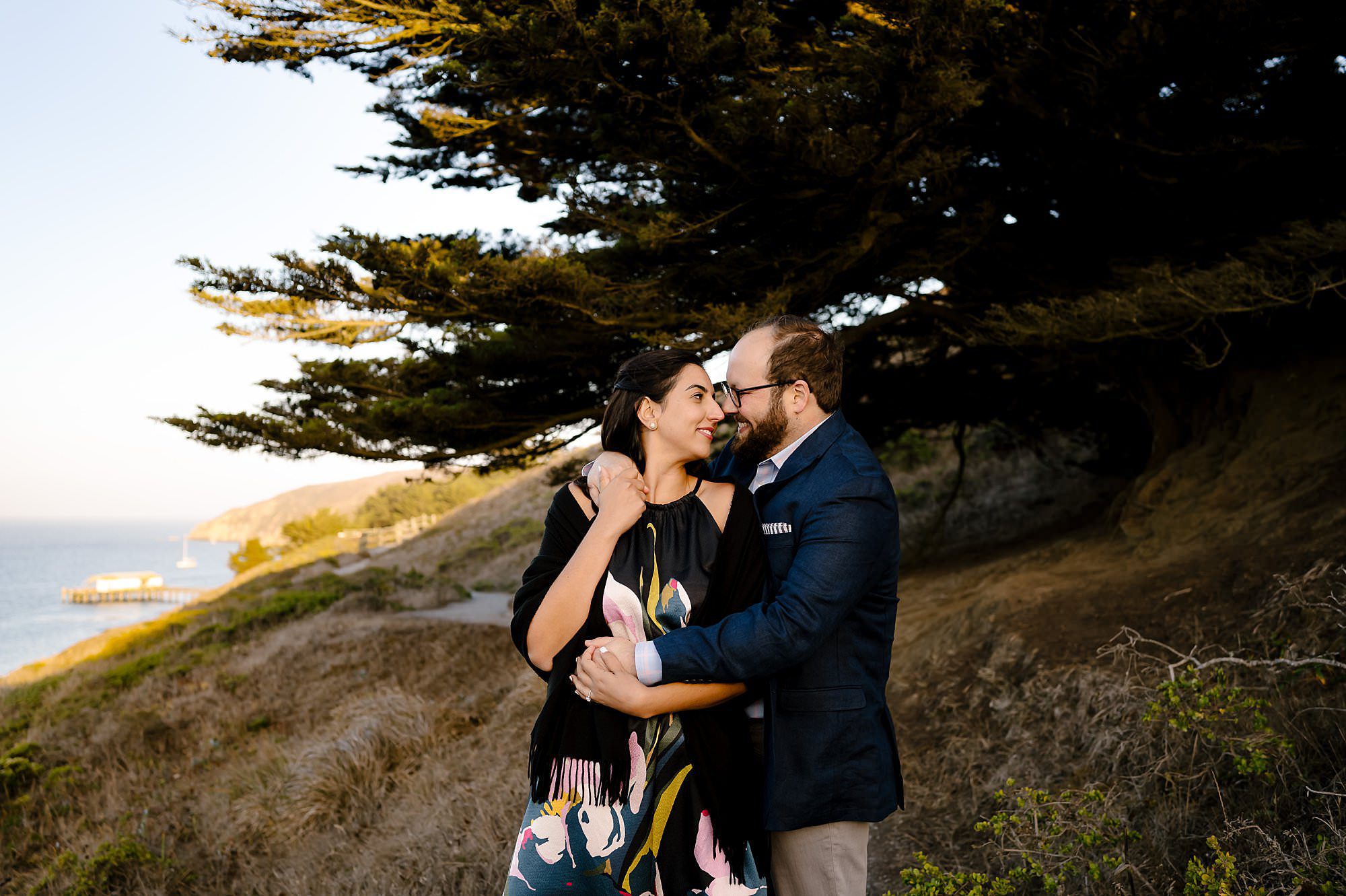 Engaged couple embracing closely during the sunset on a hike to Chimney Rock in Pt Reyes