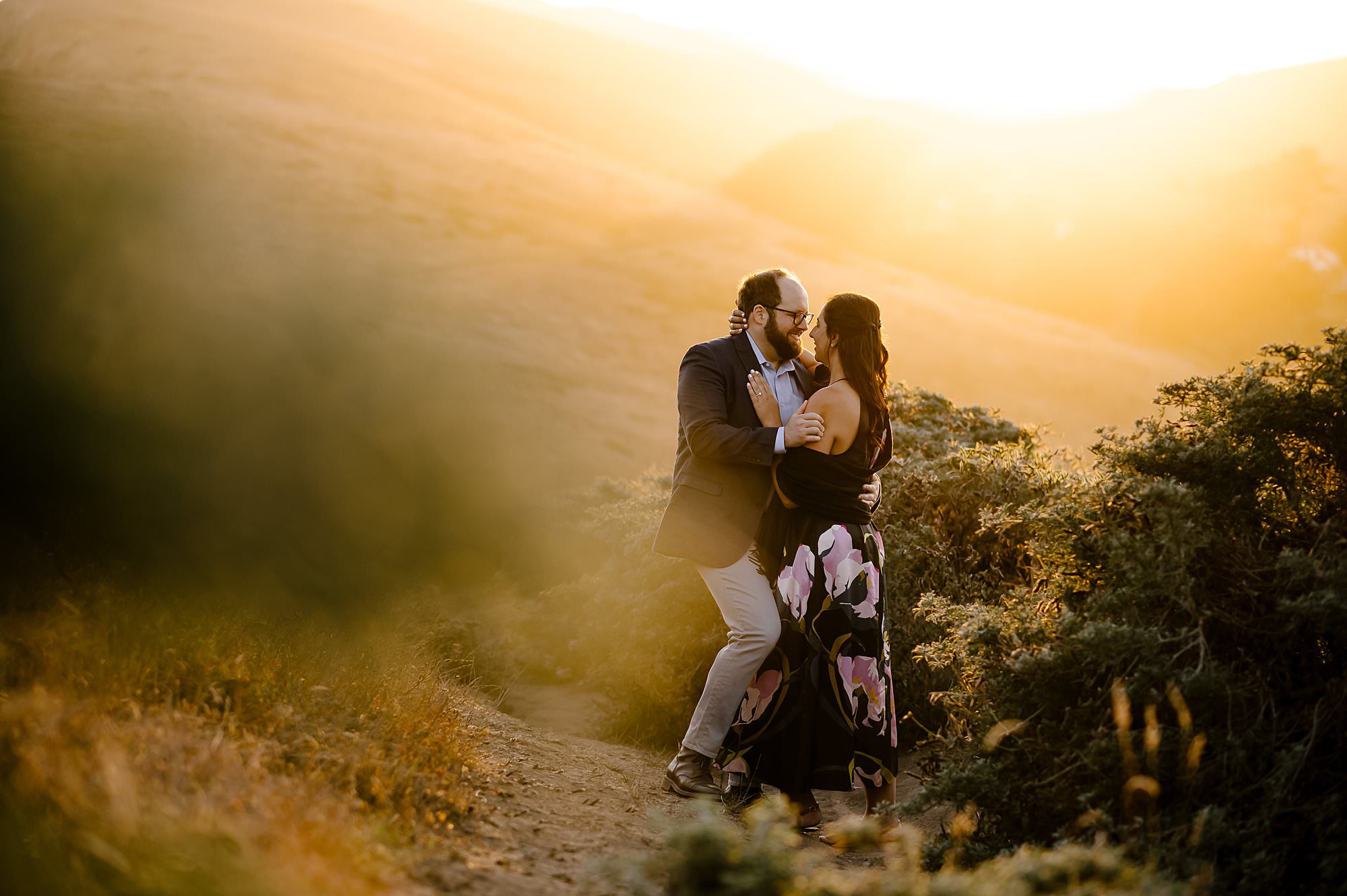Engaged couple embracing in the sunset on a hike to Chimney Rock in Pt Reyes