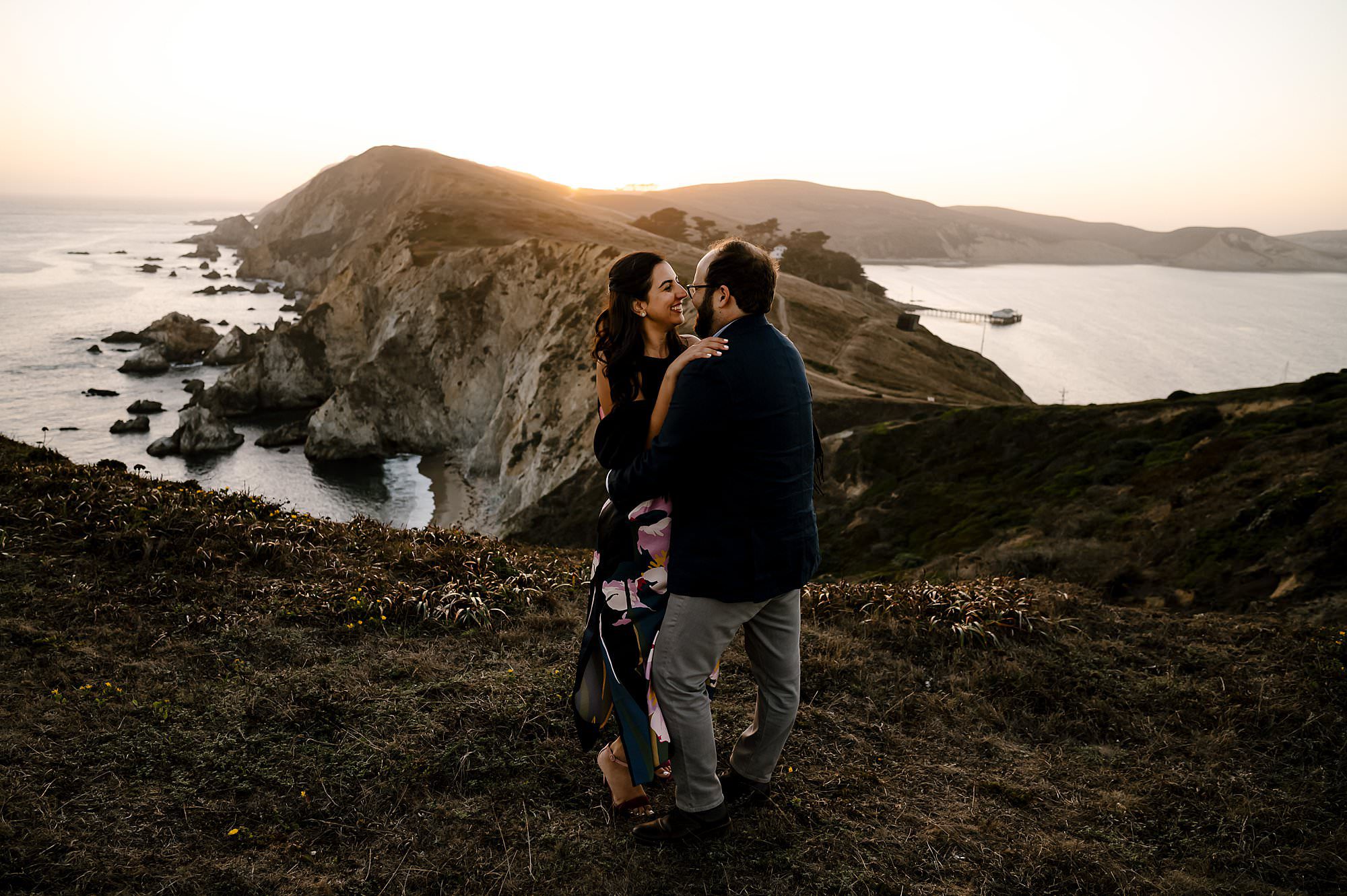 Engaged couple embracing in the sunset on a hike to Chimney Rock in Pt Reyes