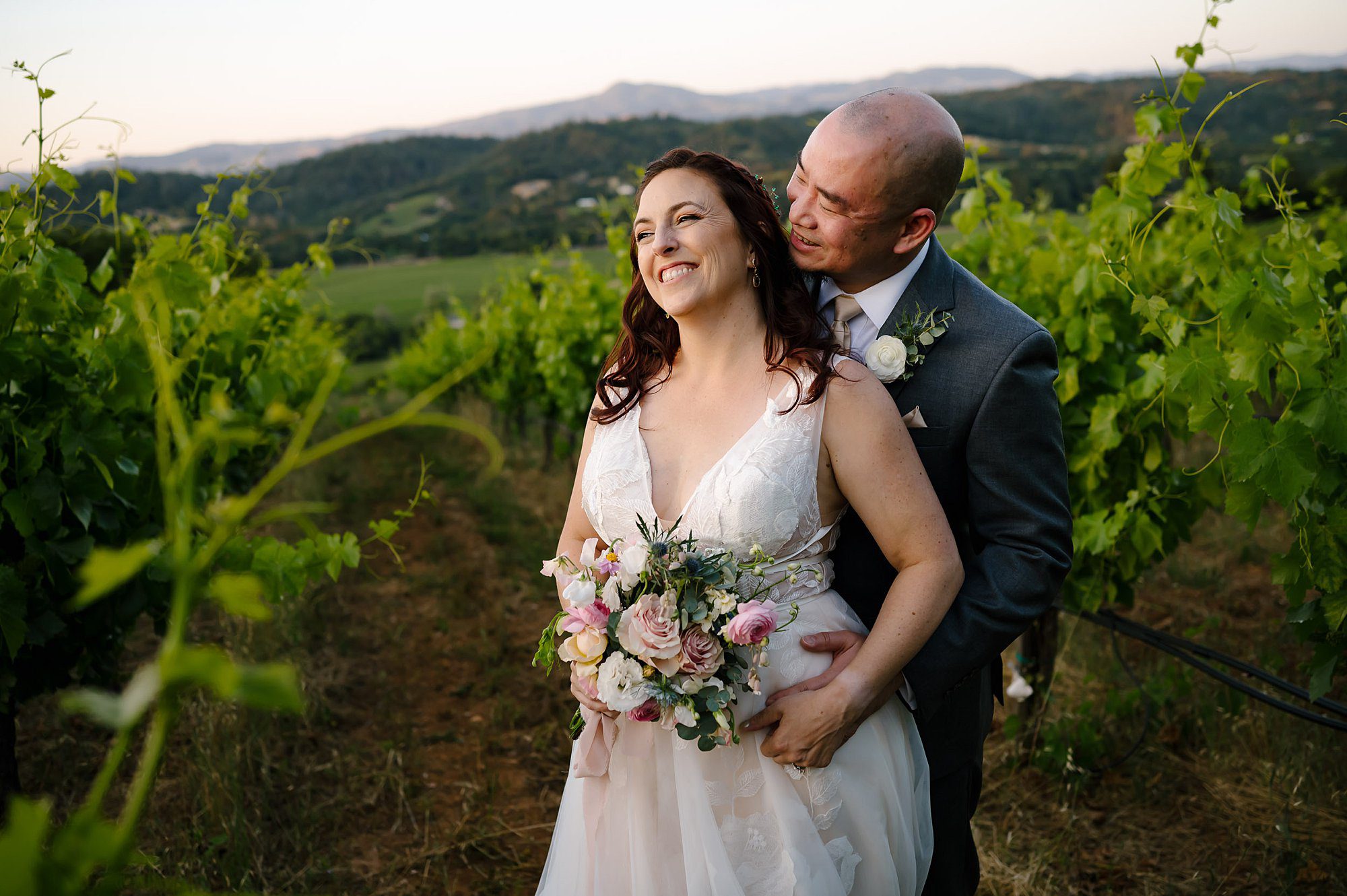 Dan and Megan embracing in the vineyard overlooking Capo Creek Winery at Sunset