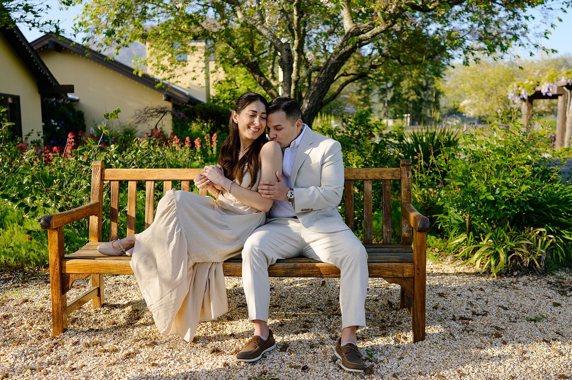 Nik kissed Jackie shoulder while they sit on the bench in the garden at Landmark Vineyards