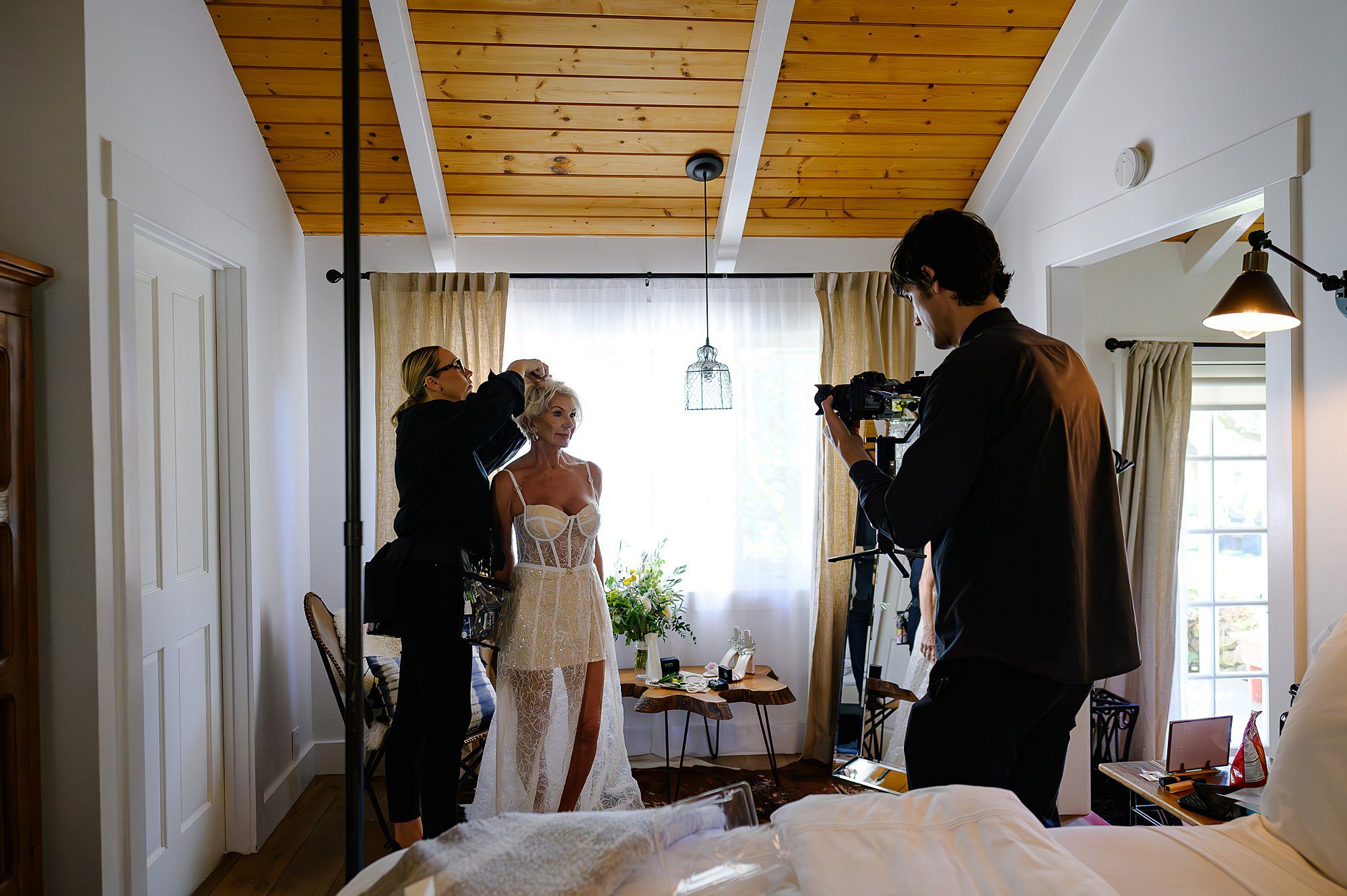 Videographer xx filming Carrie Aldous putting the finishing touches on Lynn's hair before she heads to her elopement in the vineyard at Beltane Ranch.