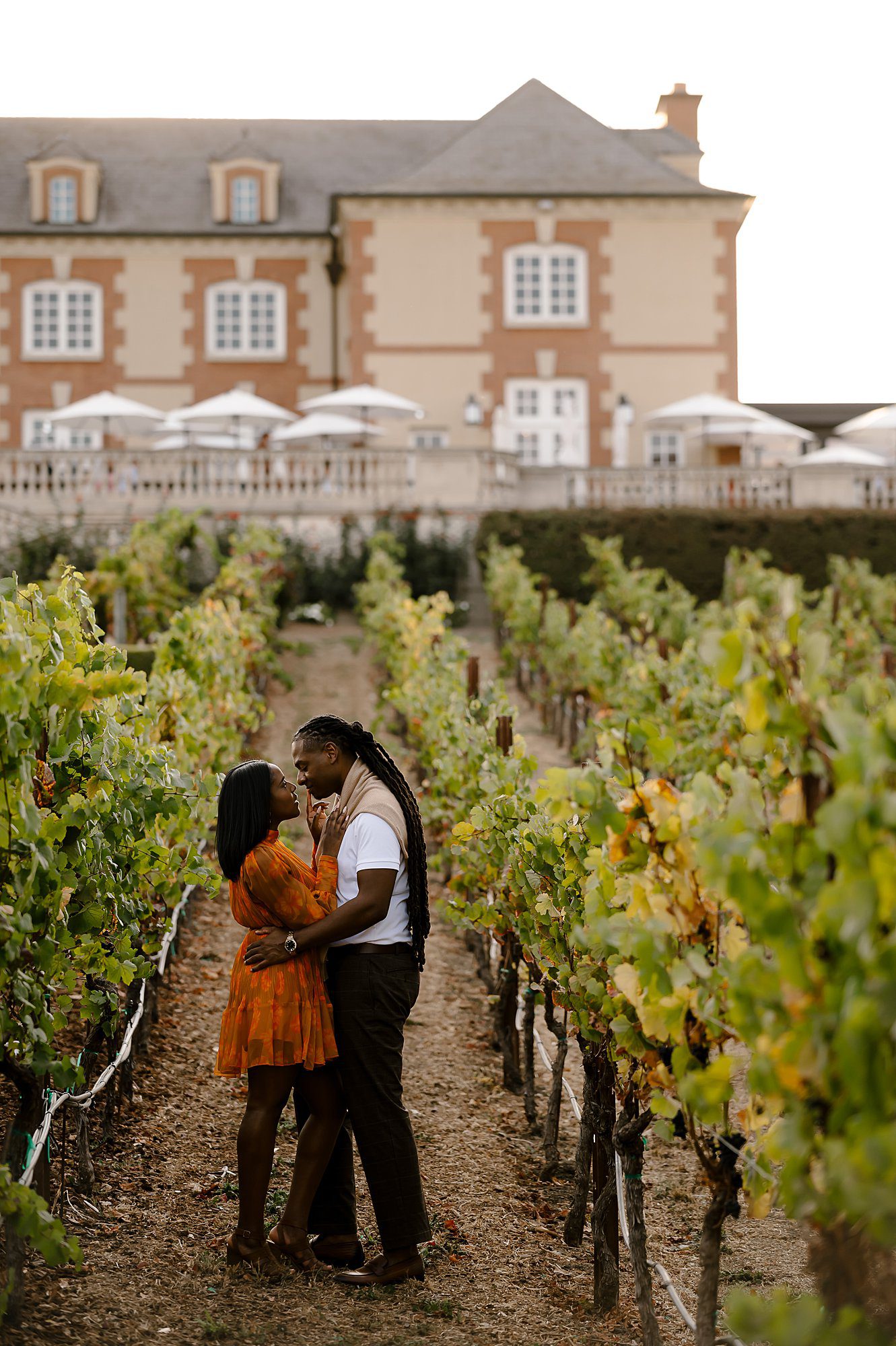 Chris and Tiara embrace in vineyard in front of Domaine Carneros after he proposed