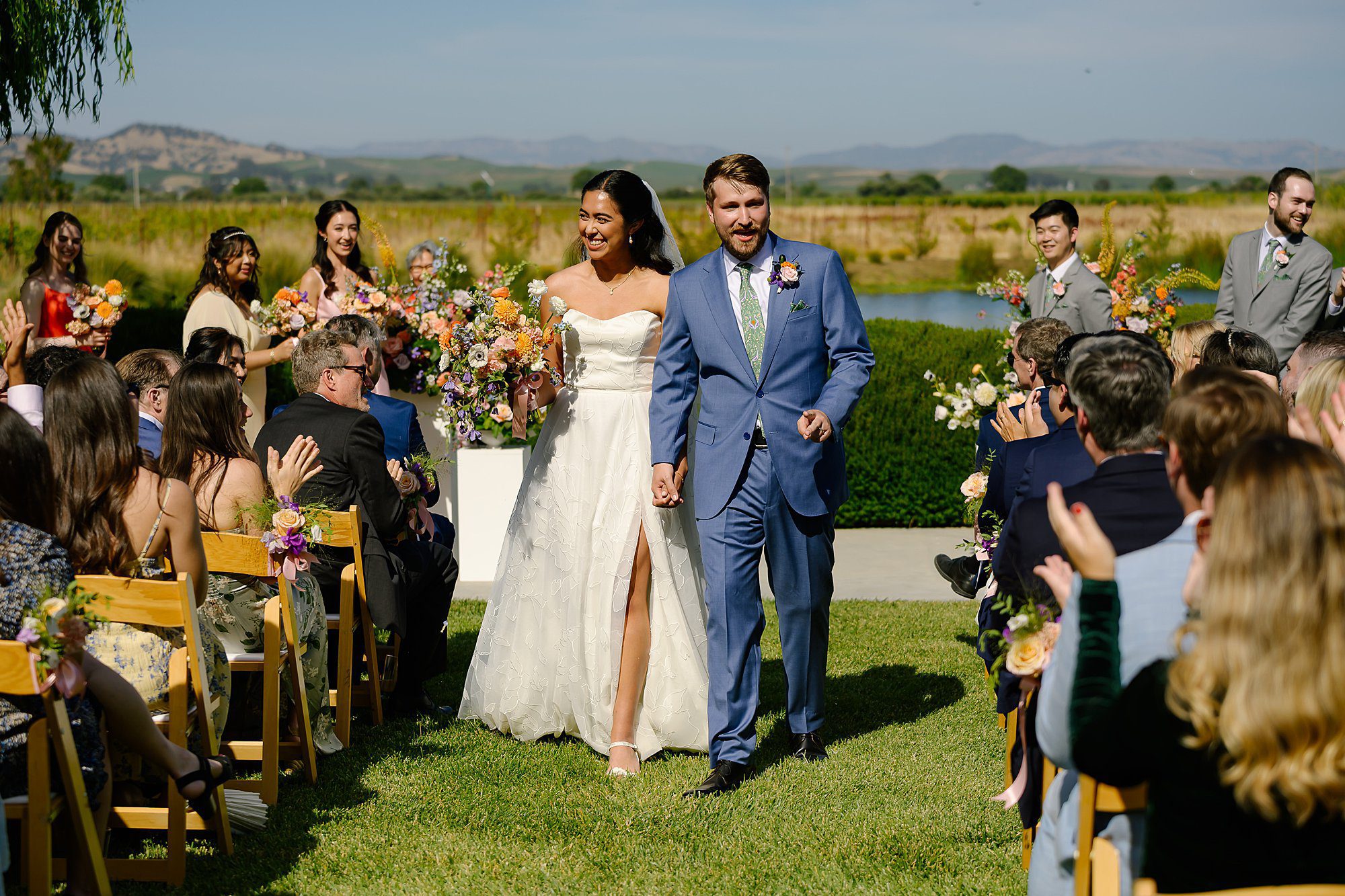 Scott and Camille laughing as they walk down the aisle after their ceremony on the lawn overlooking the vineyard at the Barn at Harrow Cellars in Sonoma CA