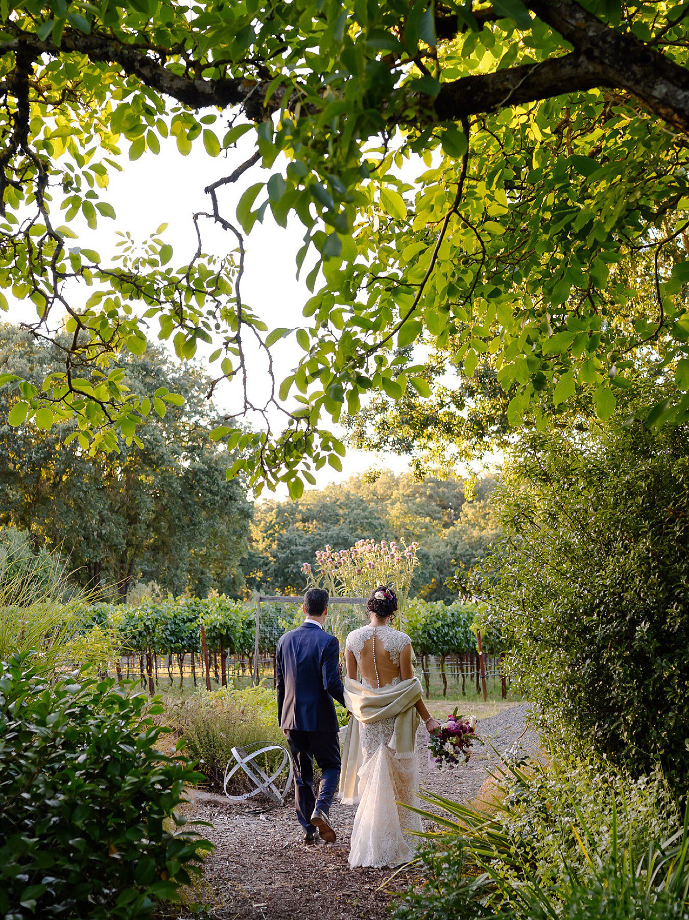 Yoni and Lara walk through the gardens of the private vineyard estate where they got married in Windsor CA