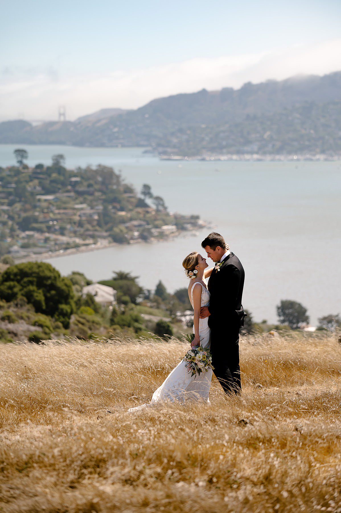Couple embraces on Tiburon Ridge overlooking San Francisco just before their wedding at Landmark Art and Garden Center
